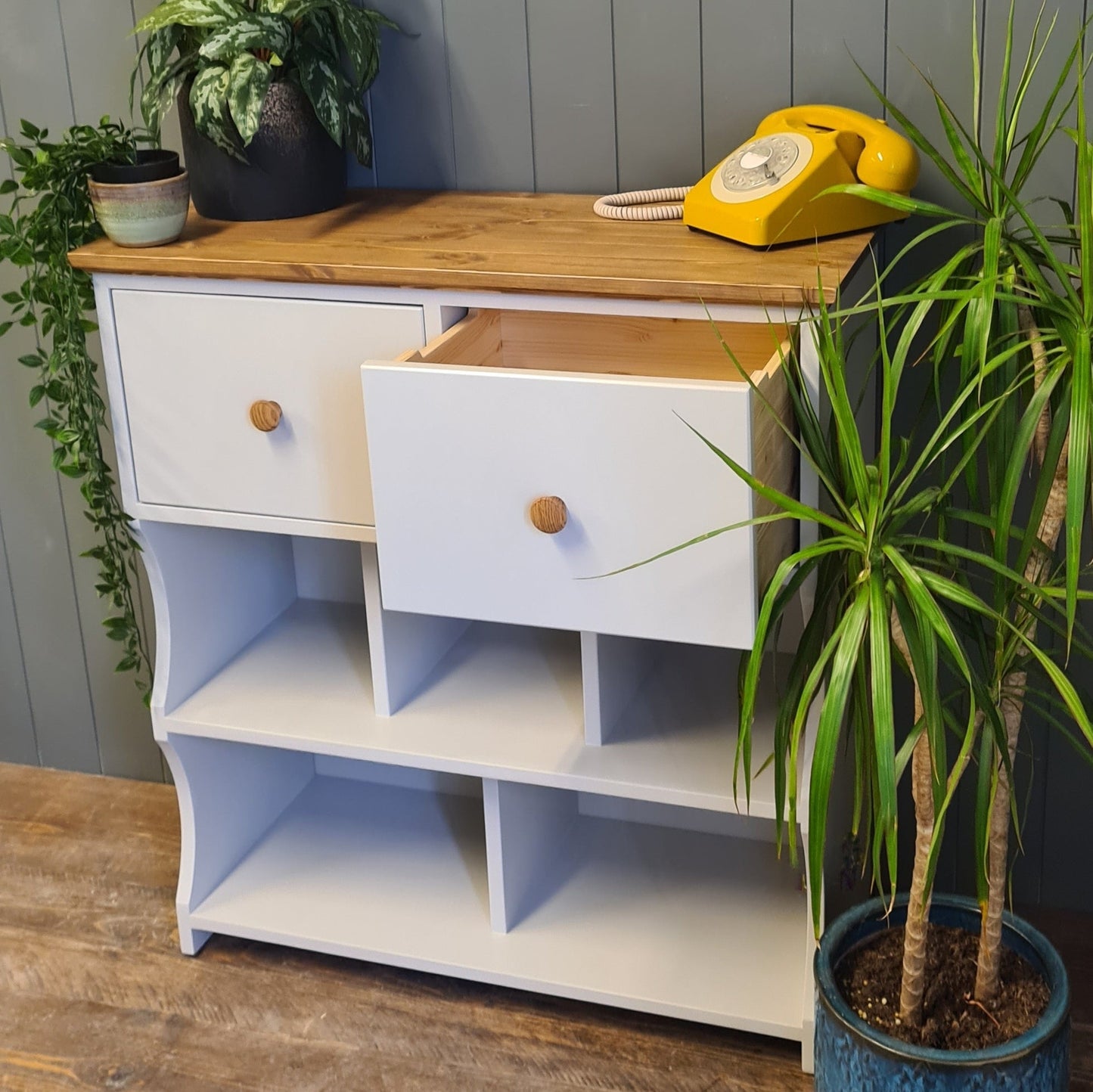 Hallway shoe rack console table. Painted french grey with an antique pine finish. Deep drawer open. Dressed with plants and rotary telephone.