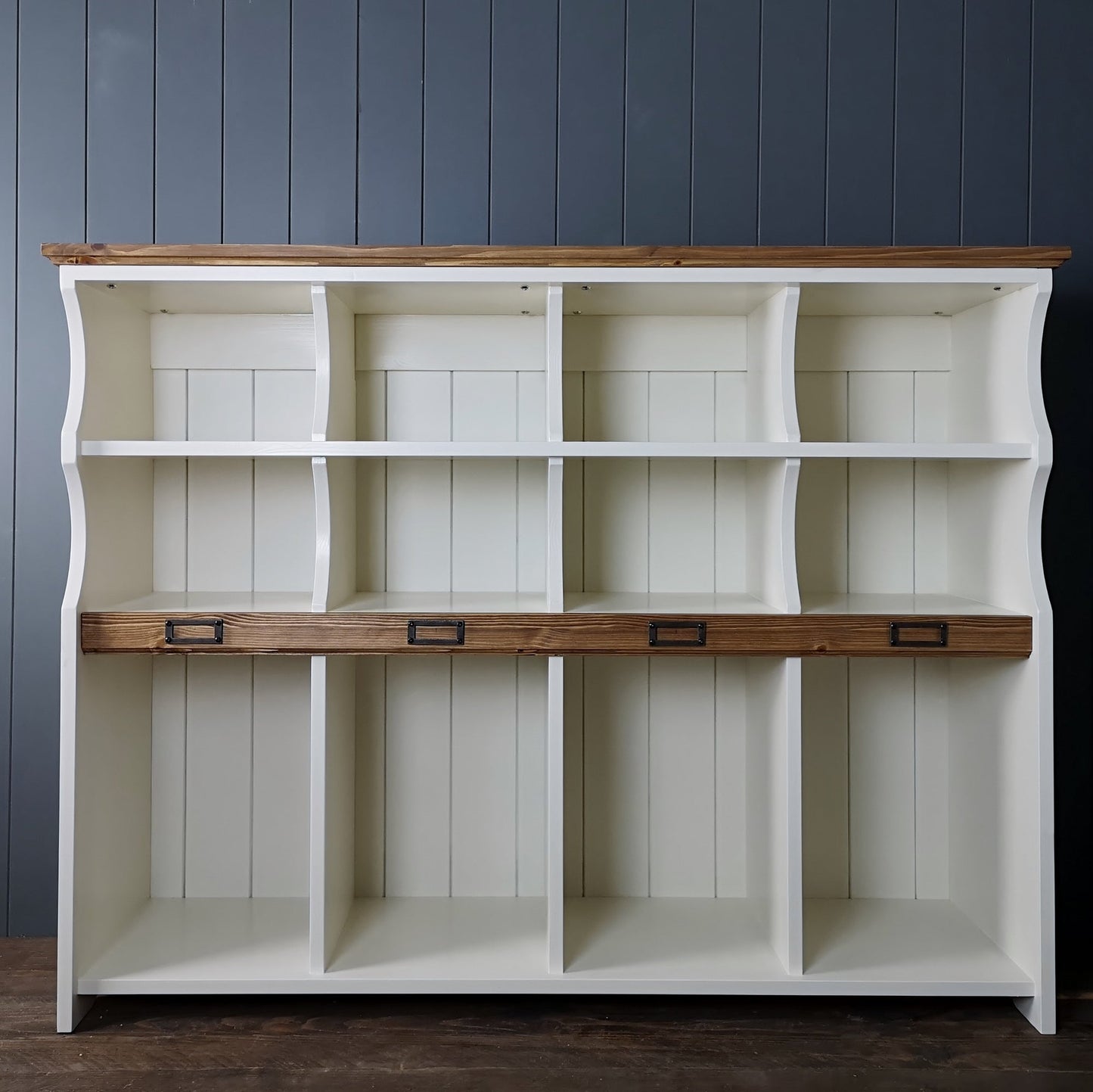 Hallway storage cabinet to organise shoes, boots, school bags & sports equipment. A row of tall compartments with two shelves of compartments above. An antique pine strip with name plaques & antique pine top. Storage station is painted in antique white.