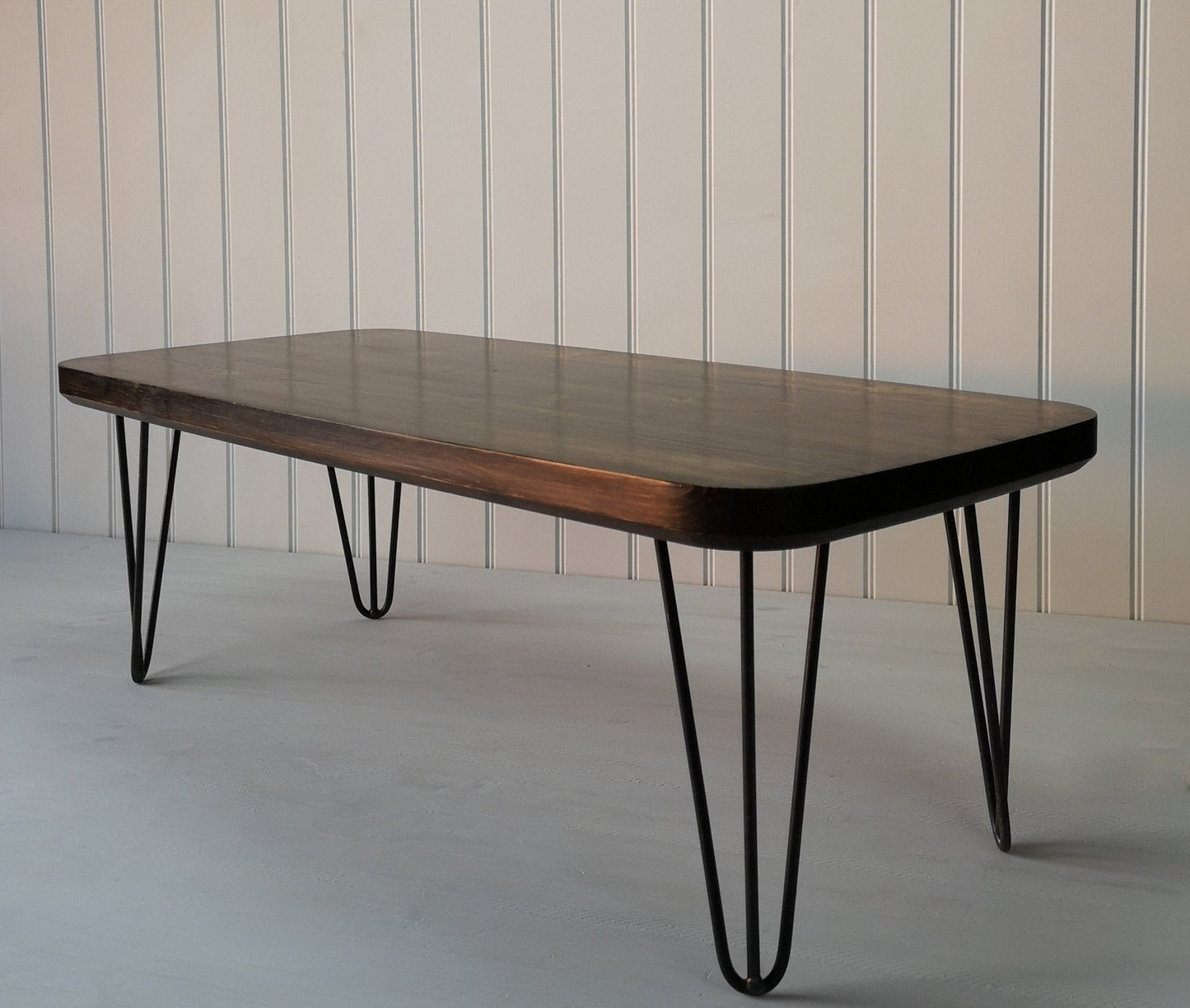 Dark wood finished rectangular coffee table with curved edges and hair pin legs
