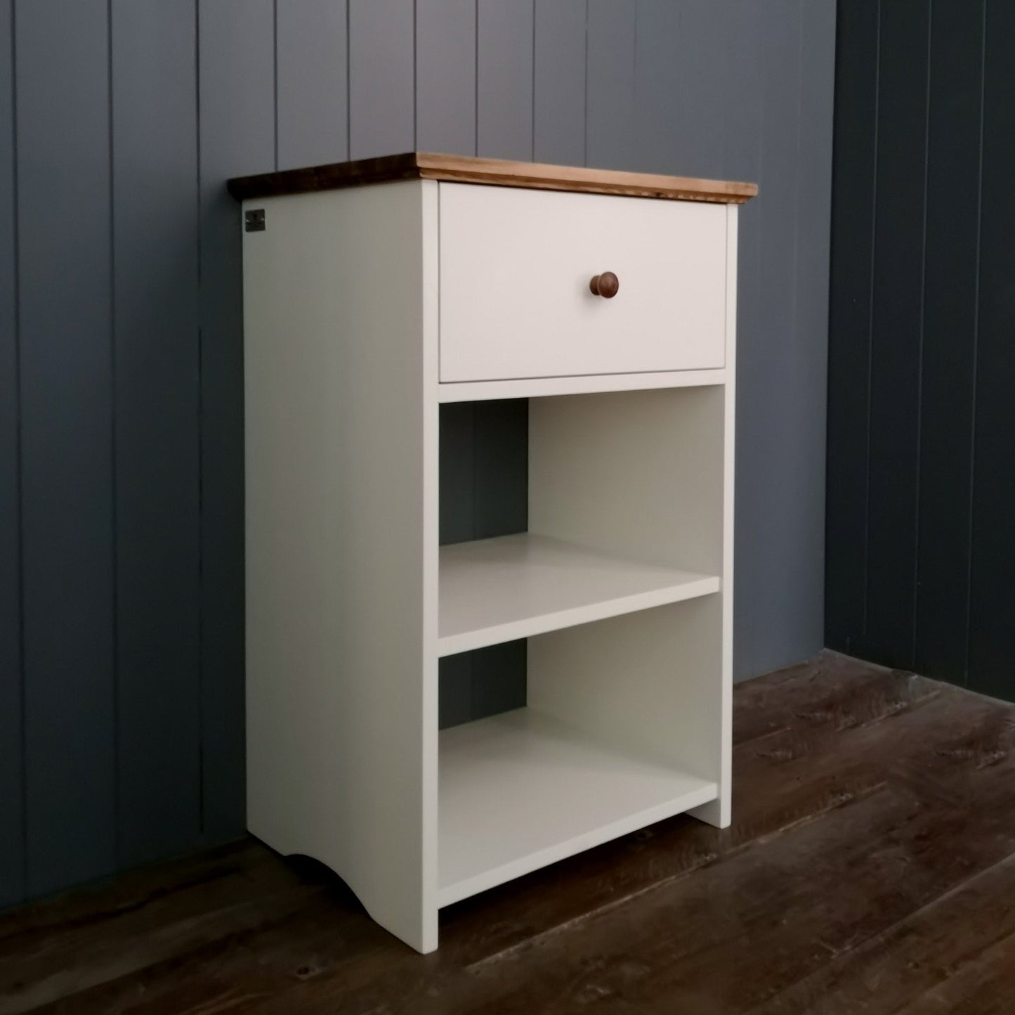 A bedside table, side table or lamp table with a shelf and deep drawer, painted white with an antique pine top.