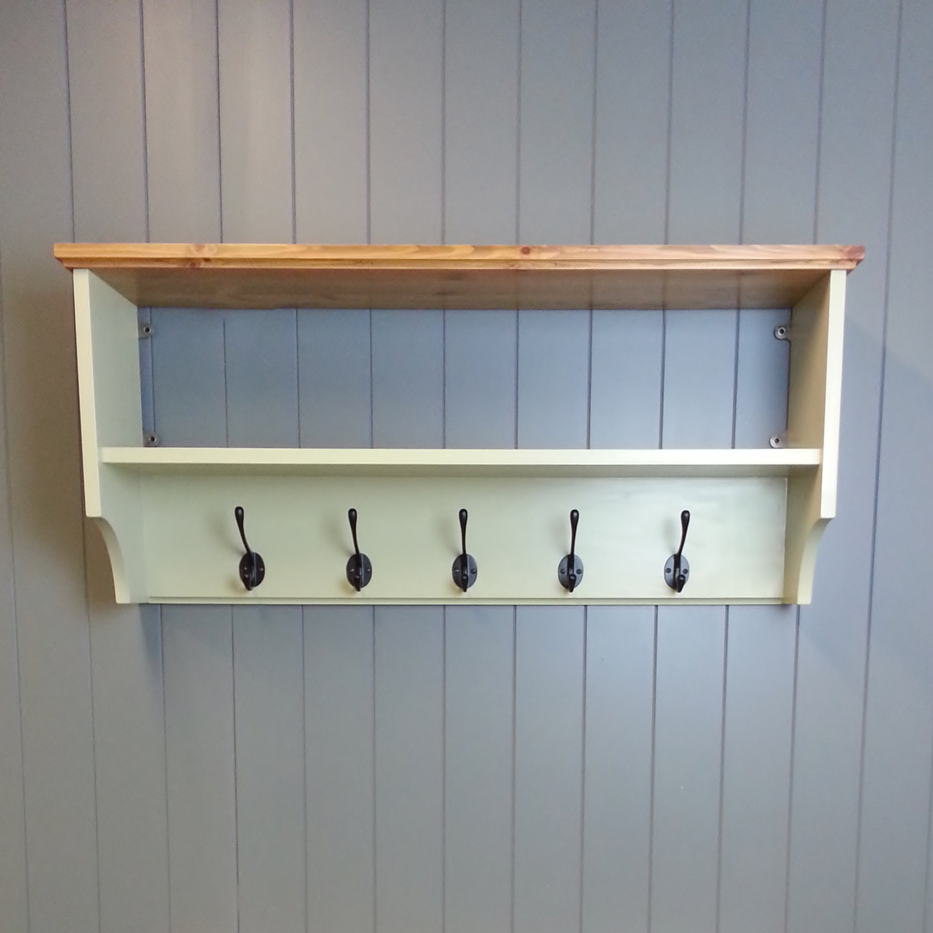 Painted coat rack with shelf and hooks.