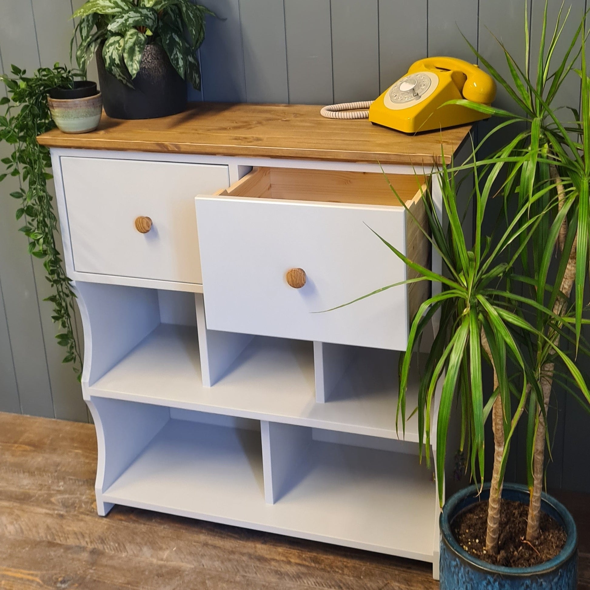 Hallway shoe rack console table. Painted french grey with an antique pine finish. Deep drawer open. Dressed with plants and rotary telephone.