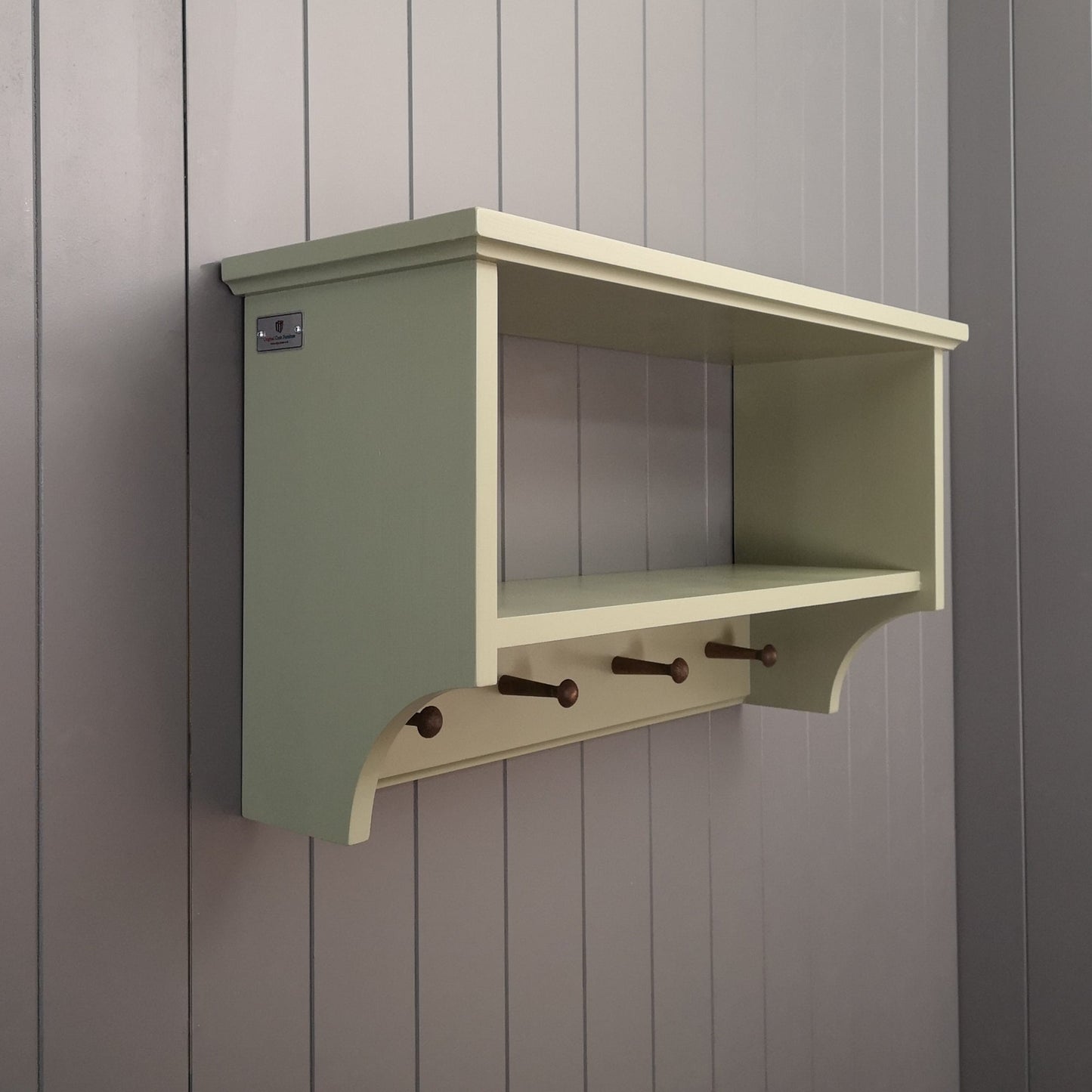 A painted hallway coat rack with a storage or display shelf and vintage style wooden pegs to hang coats.