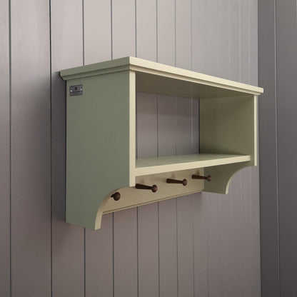 A painted hallway coat rack with a storage or display shelf and vintage style wooden pegs to hang coats.
