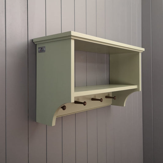A painted hallway coat rack with a storage or display shelf and vintage style wooden pegs to hang coats.